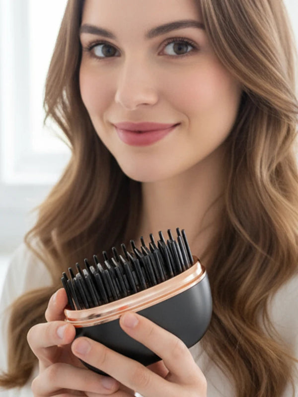 Woman holding a black and rose gold hairbrush with a blurred background